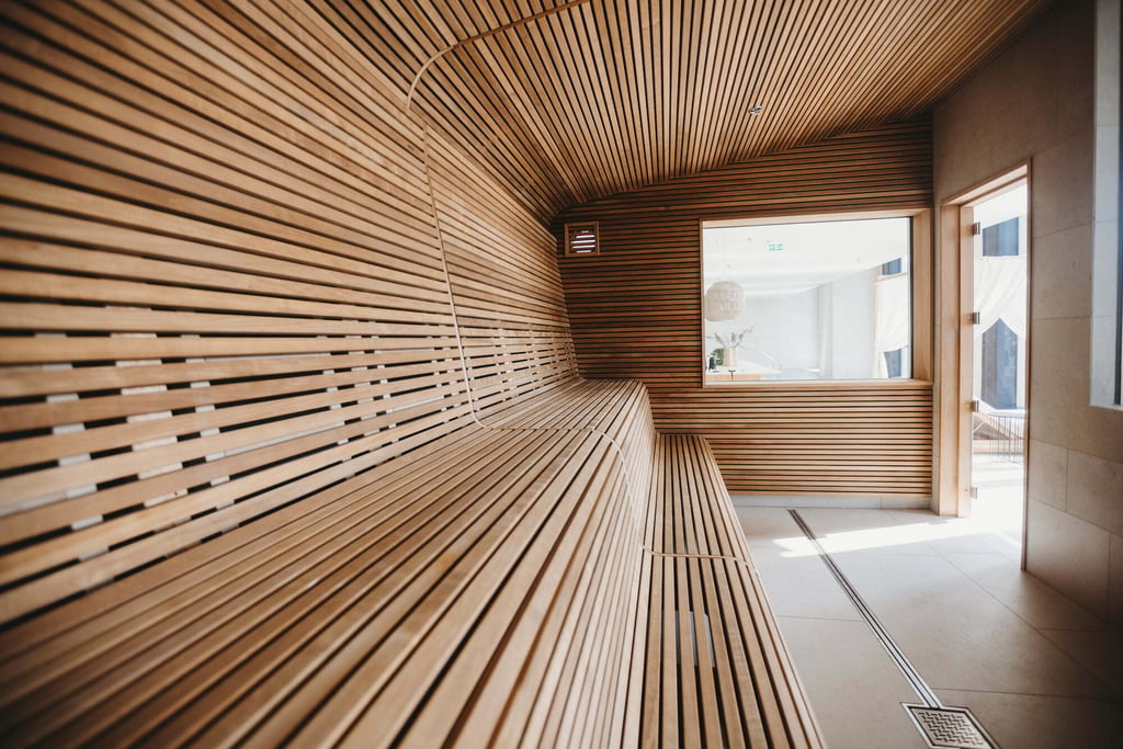 Eigentijds sauna-interieur met geribbelde houten wandpanelen, geïntegreerde verlichting en een zorgvuldig ontworpen bankenindeling.